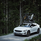 Likely insufferable person driving a white Polestar 2 with bikes on top of it down a gravel road.